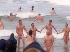 Hundreds of nudist people running into the sea bare
